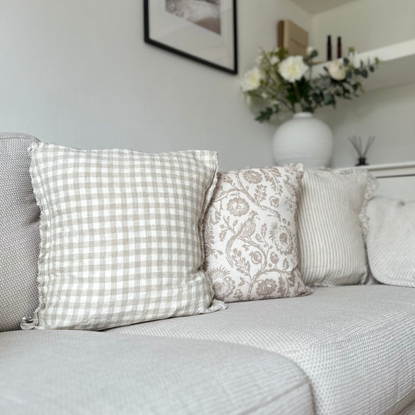 set of 3 cream and beige country style cushions sat on a cream sofa in a living room
