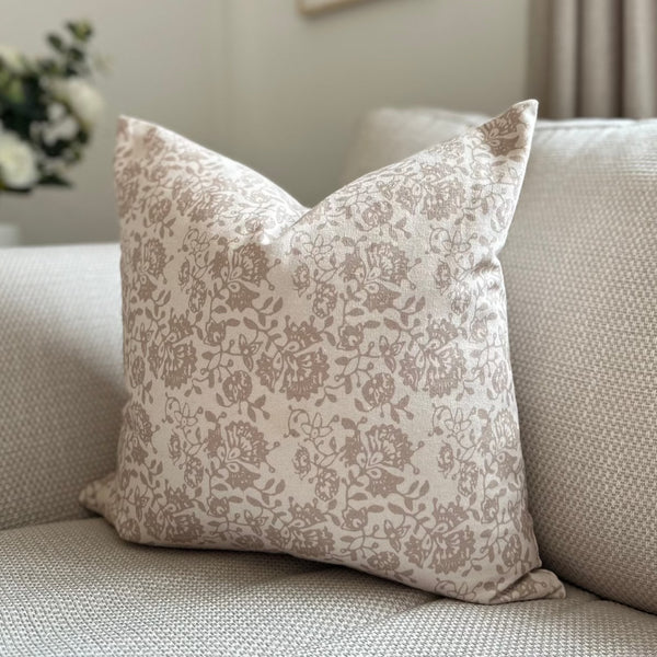 square cream cushion with a delicate taupe/beige floral pattern motif all over front and back. Sat on a cream sofa