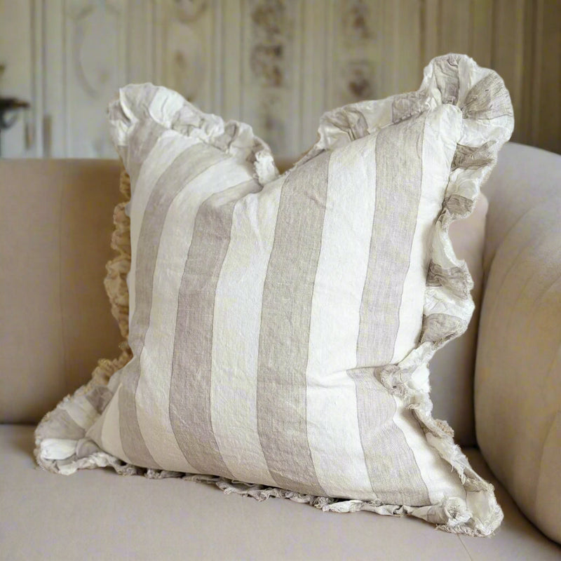 ruffled edge square cushion with a chunky vertical all over cream and neutral beige stripe. Sat on a cream sofa 
