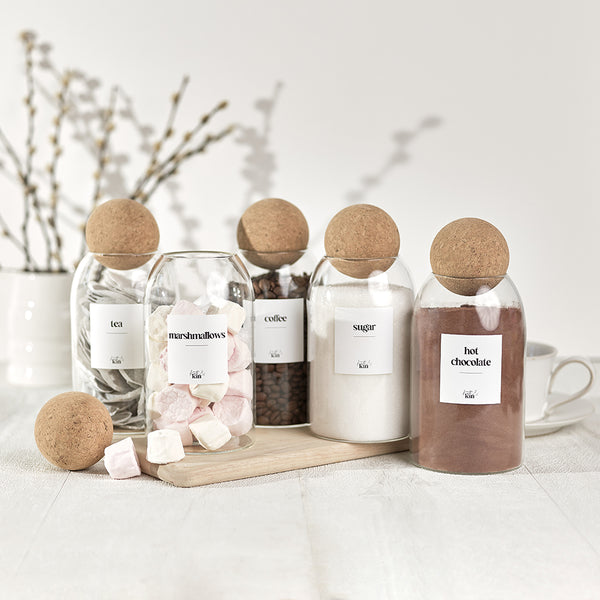 5 glass and cork jars storing tea coffee sugar hot chocolate and marshmallows